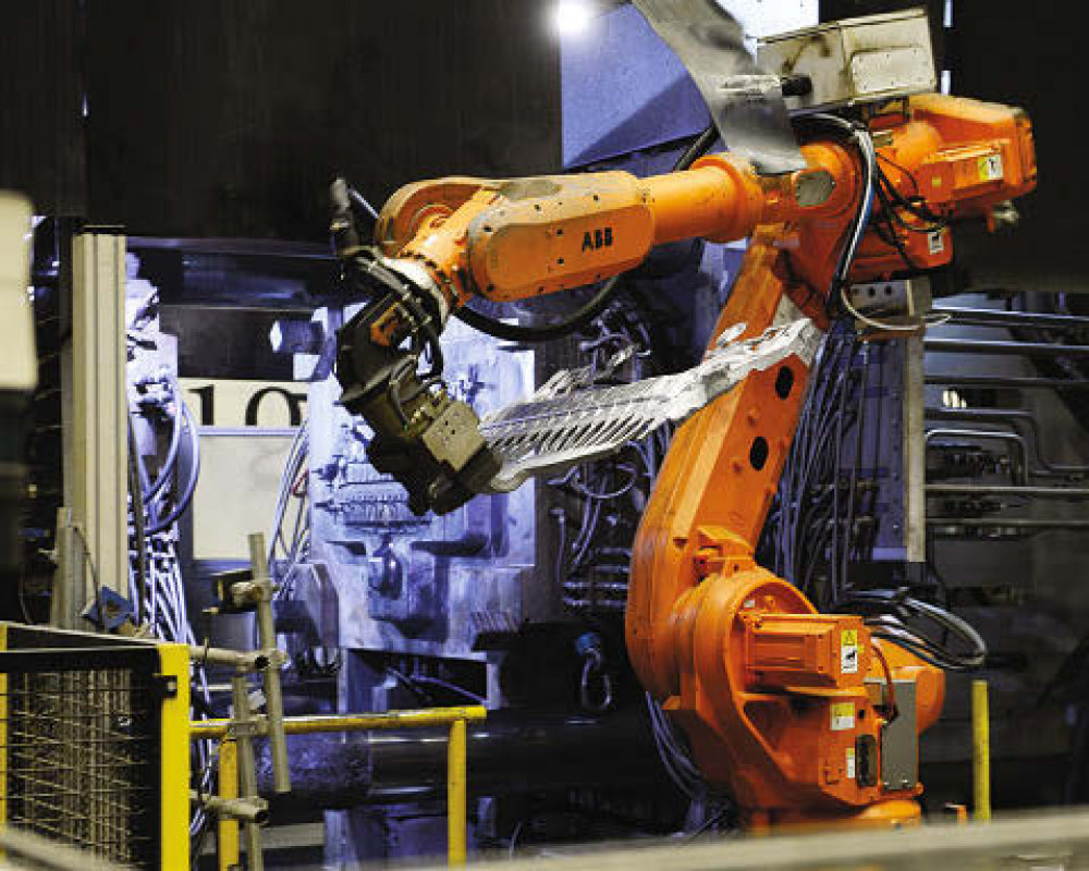 Ein Industrieroboter entnimmt einer Druckgießanlage ein Strukturbauteil. Rheinmetall erhält einen Großauftrag über 60 Millionen Euro. - © RHEINMETALL