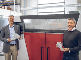 Geoff Gardner, Innovation Director Additive Manufacturing bei Covestro (li.) und James Reeves, Global Director for Polymer Printing bei voxeljet vor der VX1000 HSS.